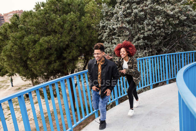 Laughing couple walking on bridge — Stock Photo