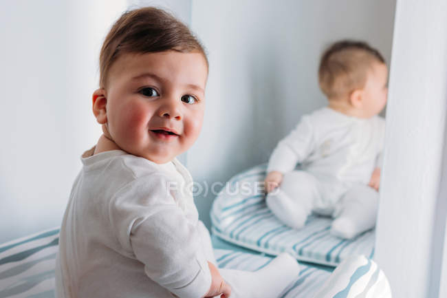 Niño sentado frente a un espejo - foto de stock