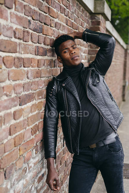 Uomo nero appoggiato sul muro di mattoni — Foto stock