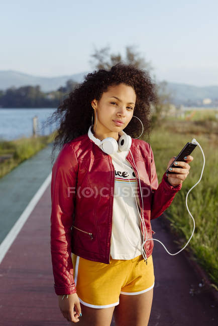 Mulher de pé com smartphone no campo — Fotografia de Stock