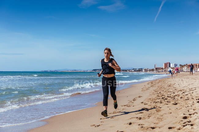 Mujer corriendo a lo largo de Sandy Beach - foto de stock
