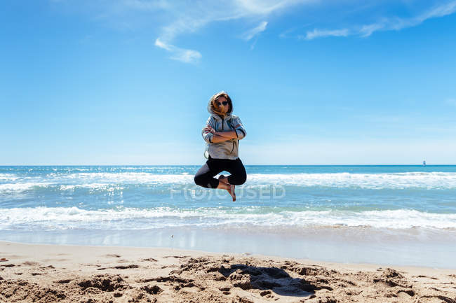 Mujer saltando en la playa de arena - foto de stock