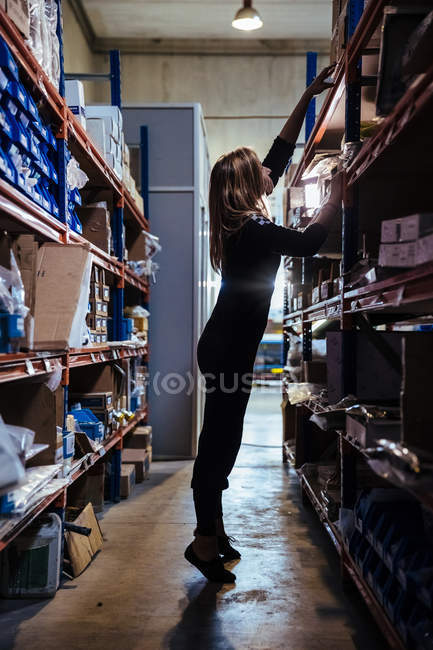Femme debout à côté des étagères — Photo de stock