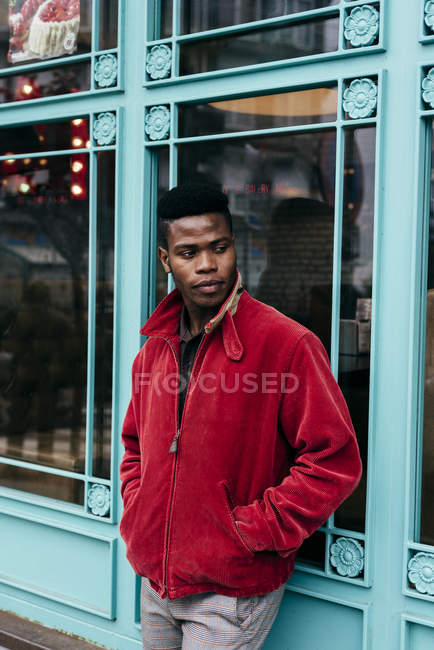 Man in red jacket standing against cafe — Stock Photo
