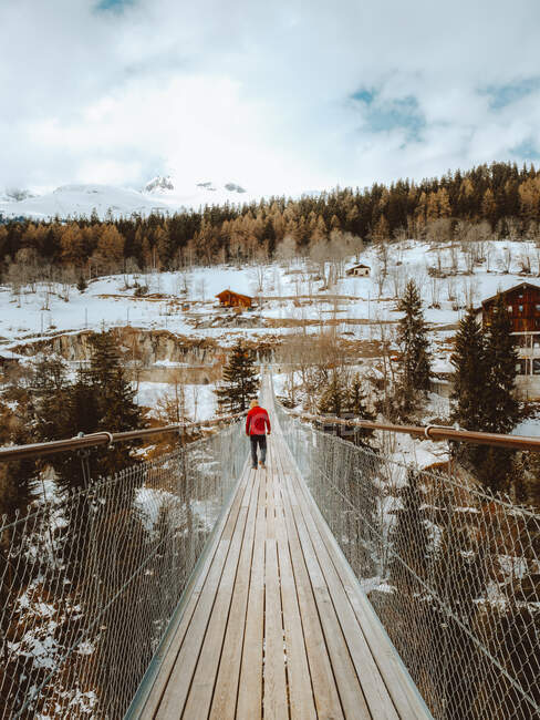 Back view of tourist man walking on wooden bridge in winter nature, Hngebrcke Frgangen - Mhlebach, Switzerland — Stock Photo