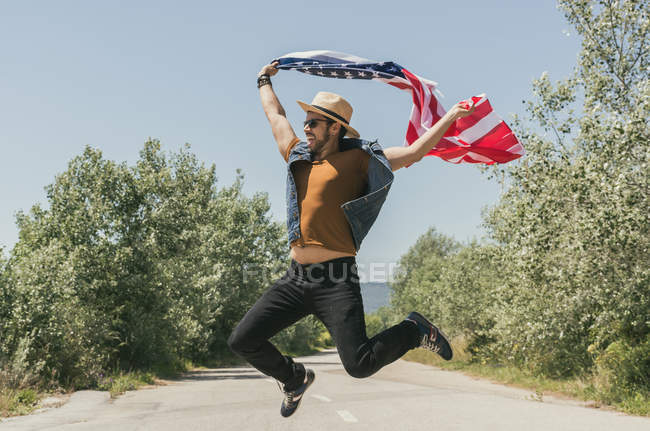Hombre saltando con bandera americana - foto de stock
