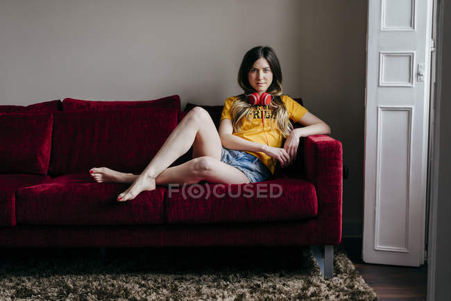 Жінка з навушниками сидить на дивані — стокове фото