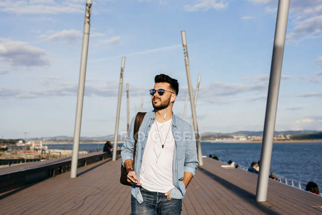Hombre con mochila paseando por el paseo marítimo - foto de stock
