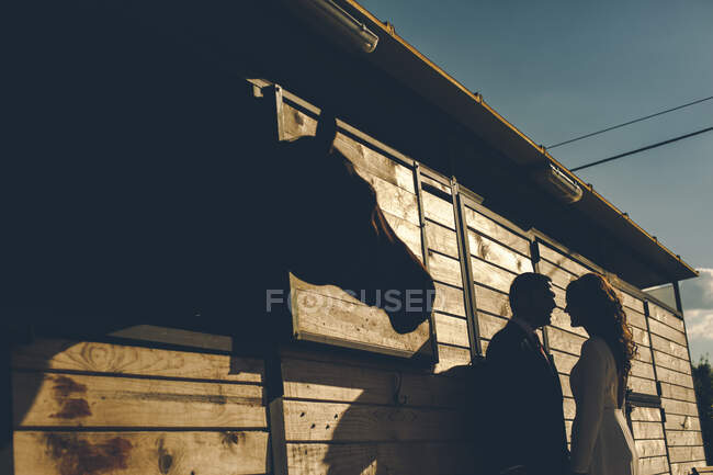 Aufnahme der Silhouette eines Paares, das im Garten am Haus steht. — Stockfoto