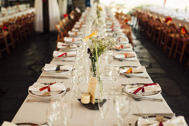 Vue sur une longue table de banquet avec assiettes préparées pour la célébration. — Photo de stock