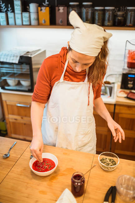 Femme mettant des épices à la soupe — Photo de stock