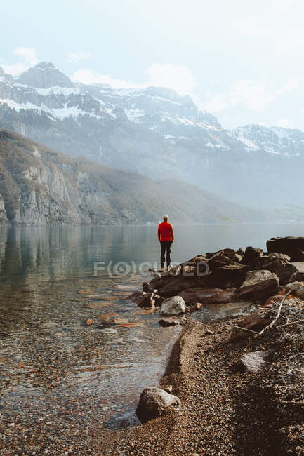 Vista laterale del turista adulto in piedi sul lago calmo in montagna, Walensee, Svizzera — Foto stock