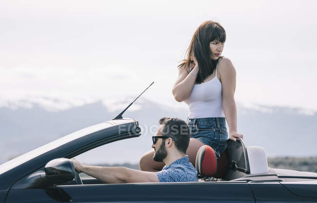 Hombre y mujer viajan en coche descapotable. - foto de stock