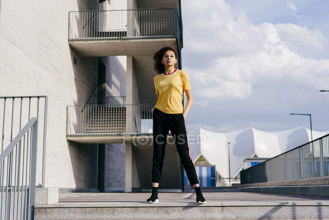 Deportiva mujer de pie frente al edificio - foto de stock