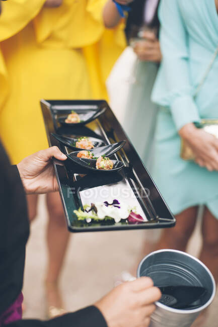 Unrecognizable waiter holding tray with grape and cheese canape. — Stock Photo