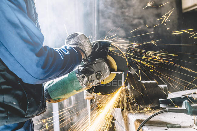 Uomo lavora con smerigliatrice taglio metallo. — Foto stock