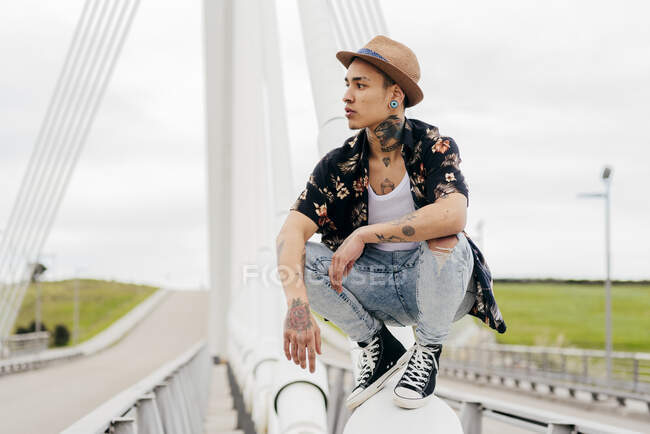 Хипстер сидит на перилах моста — стоковое фото