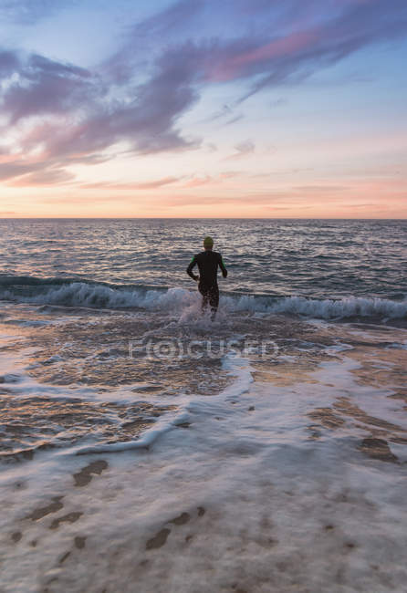 Триатлон, бегущий в волнистом море — стоковое фото