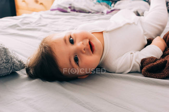 Chico bebé divertido acostado en la cama - foto de stock