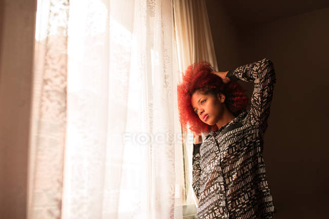 Donna in piedi accanto alla finestra — Foto stock