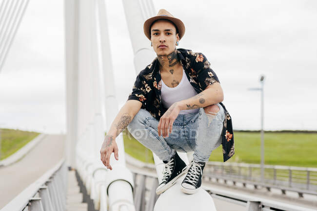 Хипстер сидит на перилах моста — стоковое фото