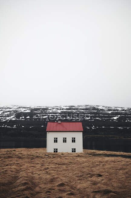 Pequeña casa con techo rojo construida en la colina nevada en Islandia - foto de stock