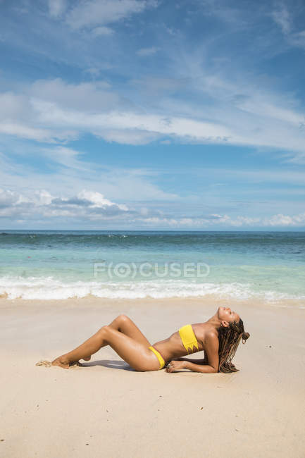 Жінка в бікіні лежить на пляжі — стокове фото