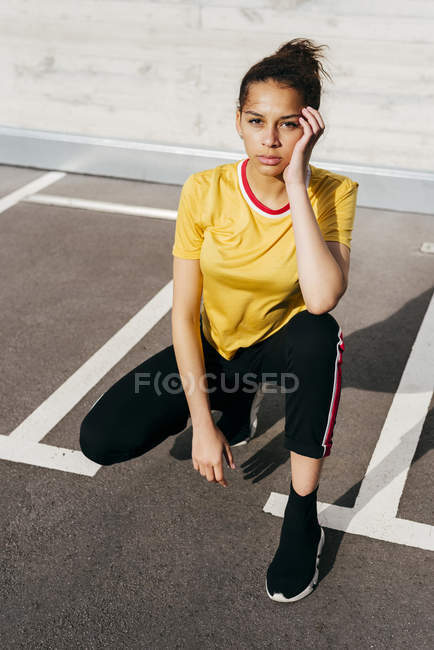 Fit woman crouching on parking lot — Stock Photo