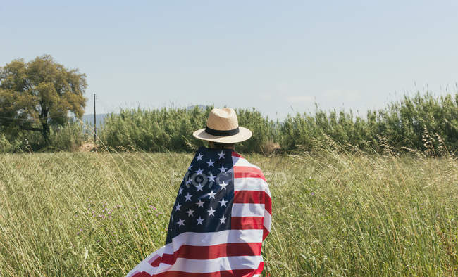 Man in hat wrapped American flag — Stock Photo