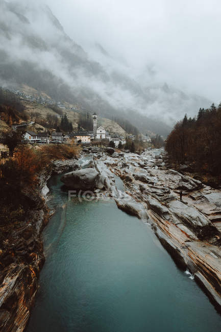Río y pequeña ciudad en las montañas - foto de stock