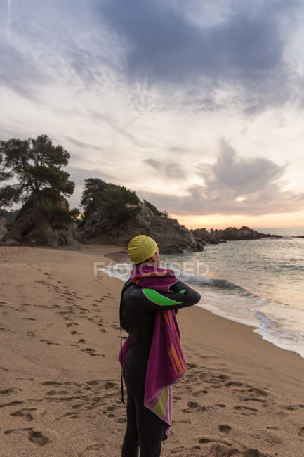 Triatleta de pie en la playa de arena - foto de stock