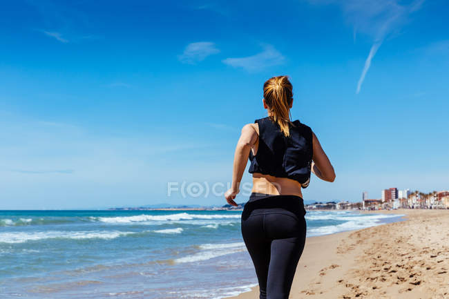 Mulher correndo ao longo de Sandy Beach — Fotografia de Stock