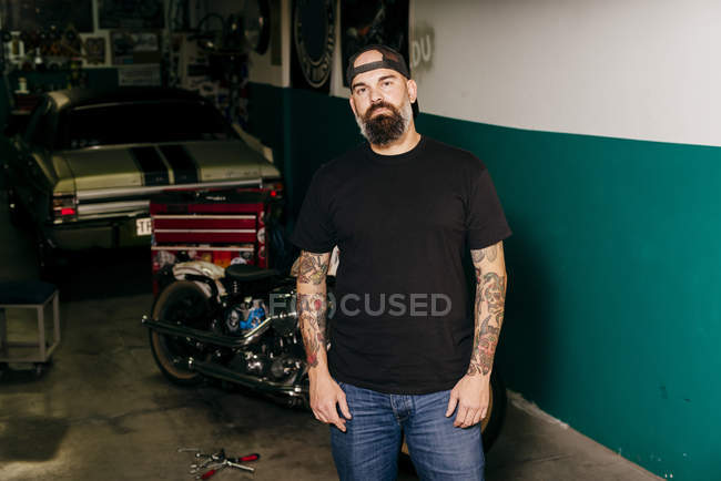 Татуйований механічний стоячи в гаражі — стокове фото