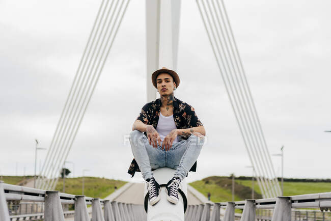 Hipster sentado no corrimão da ponte — Fotografia de Stock