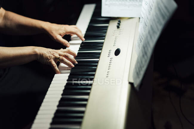 Side view of crop hands of musician sitting and playing electric piano. — Stock Photo