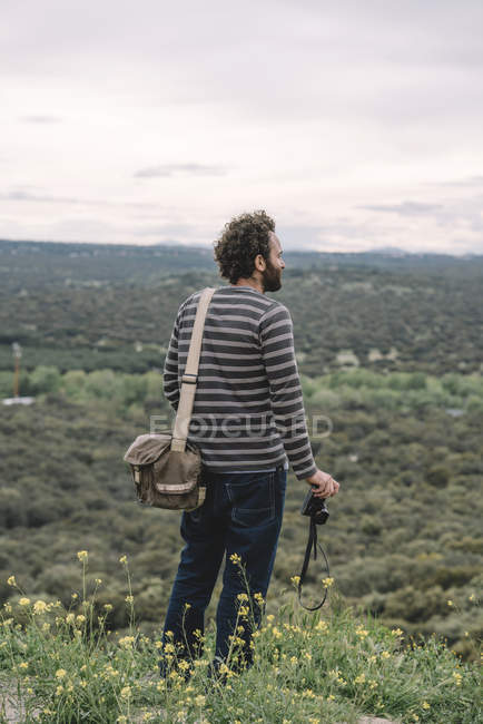 Homem de pé com câmera de fotos na natureza — Fotografia de Stock