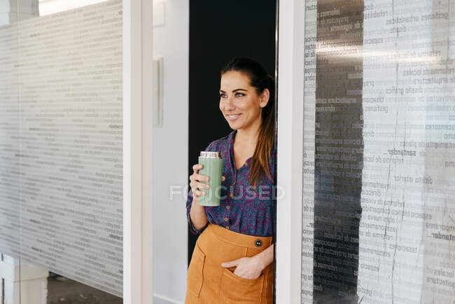 Mulher sorridente com copo no escritório — Fotografia de Stock