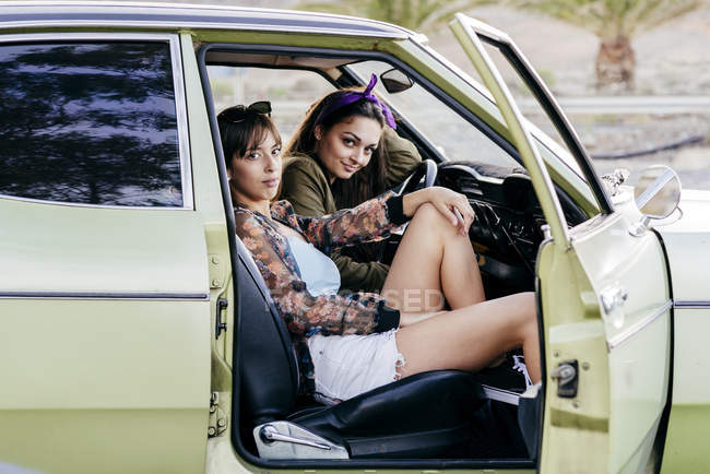 Женщины, сидящие в зеленом винтажном автомобиле — стоковое фото
