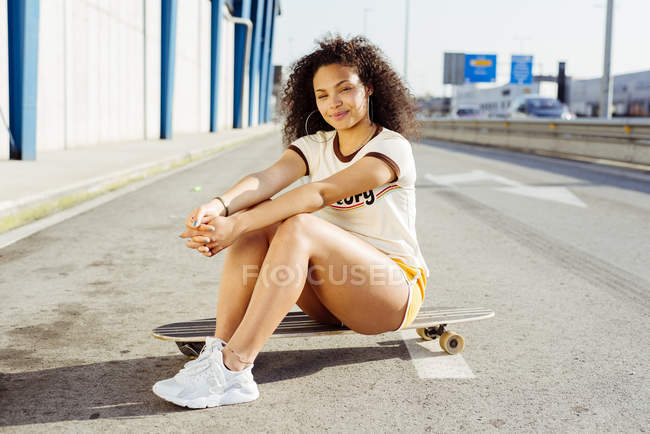Adolescente seduta su skateboard — Foto stock