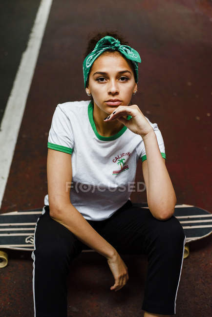 Adolescente chica sentado con longboard - foto de stock