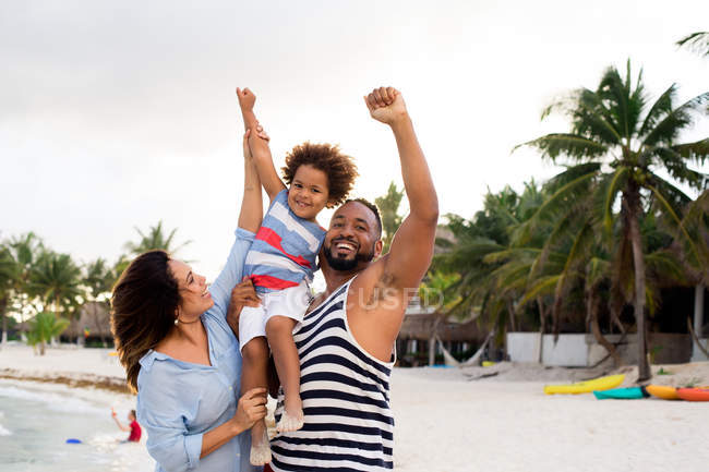 Mother and father climbing son up on beach — Stock Photo