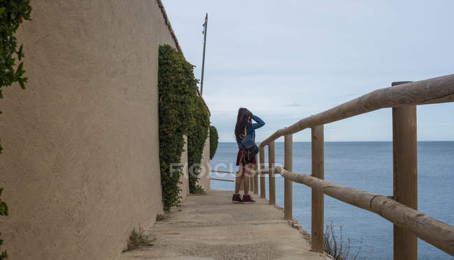 Chica de pie en barandilla en la orilla del mar - foto de stock