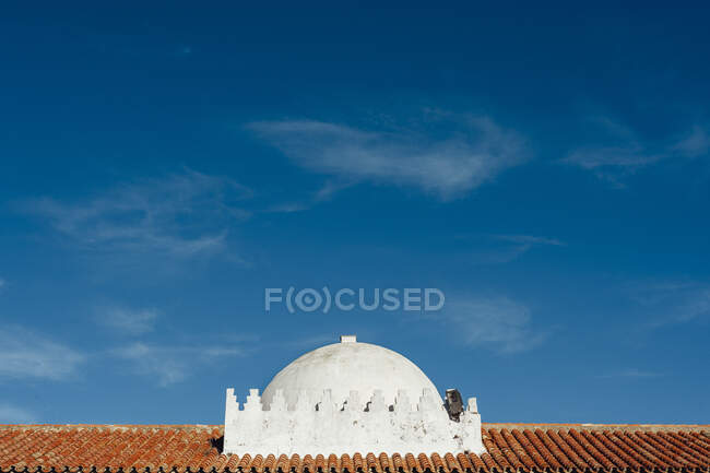 Weiße Kuppel auf orangefarbenem Dach vor blauem Himmel. — Stockfoto