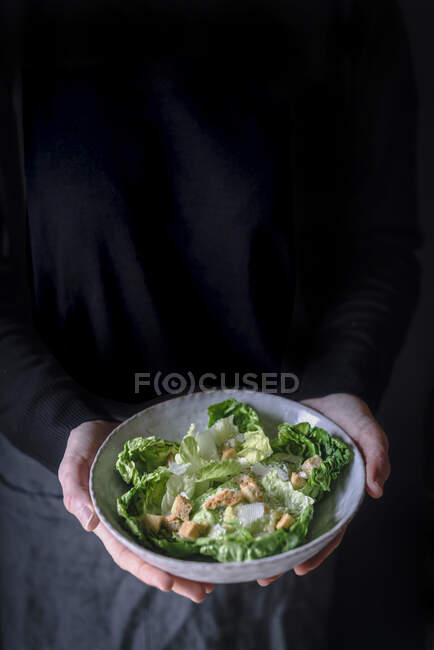Erntereife Frau in dunkler Kleidung hält Schüssel mit leckerem Salat in der Hand. — Stockfoto