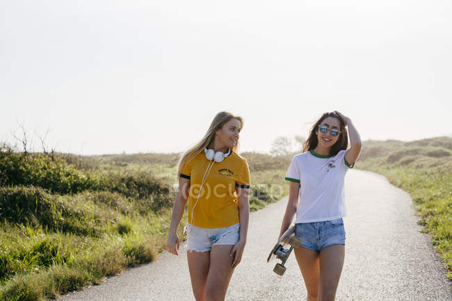 Ragazze adolescenti con longboard a piedi su strada — Foto stock