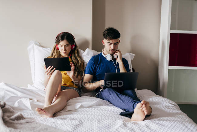 Casal usando gadgets na cama — Fotografia de Stock