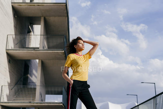 Deportiva mujer de pie frente al edificio - foto de stock