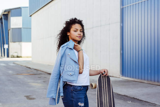 Teenage girl standing with skateboard on street — Stock Photo