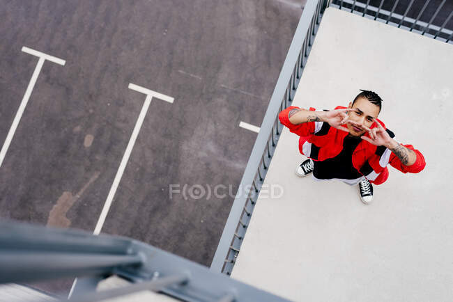 Dall'alto di fresco giovane uomo che indossa abiti casual in piedi sul tetto guardando la fotocamera — Foto stock
