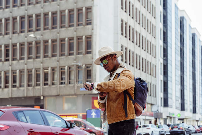Hombre negro comprobando el tiempo en la ciudad - foto de stock